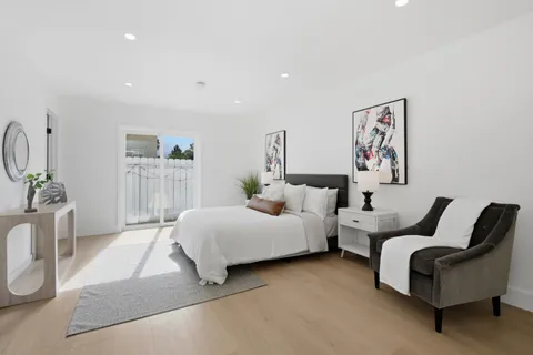 a spacious bedroom with a bed a couch and paintings on the wall