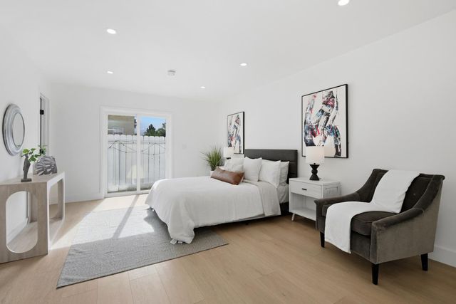 a spacious bedroom with a bed a couch and paintings on the wall