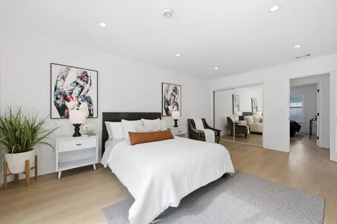 a spacious bedroom with a large bed and paintings on the wall