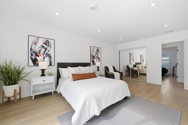 a spacious bedroom with a large bed and paintings on the wall