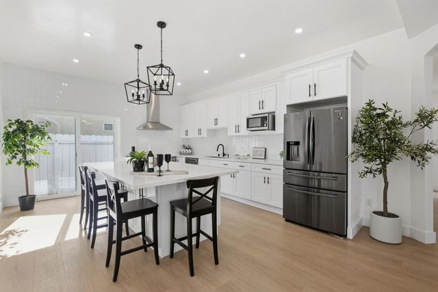 a kitchen with stainless steel appliances a dining table chairs stove and refrigerator