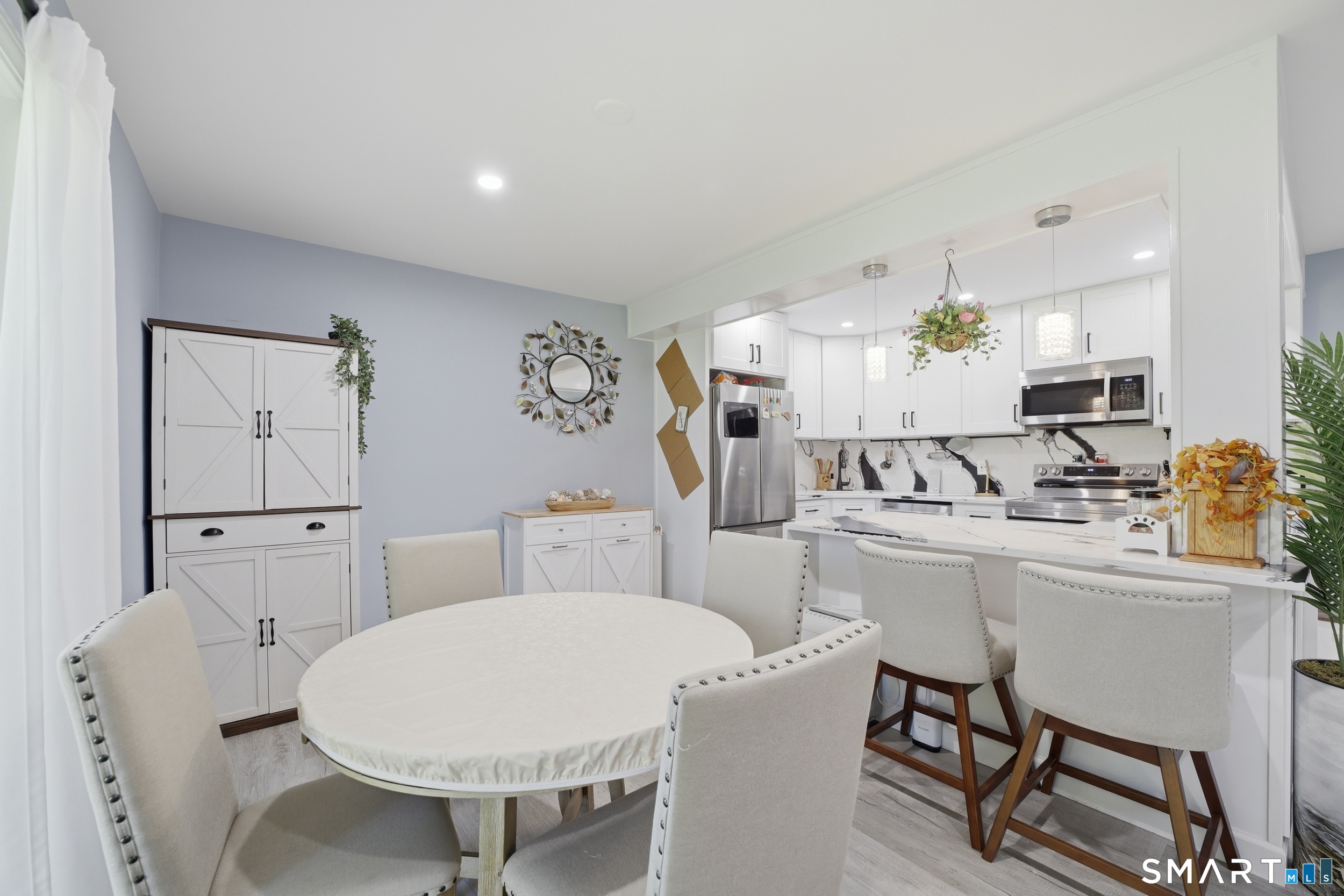 187 Flax Hill Road, Unit D1 Norwalk, CT 06854 - Photo 9 of 32 a kitchen with stainless steel appliances a white table chairs and a refrigerator