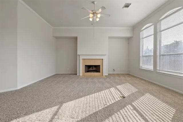 a view of a livingroom with a fireplace a ceiling fan and windows