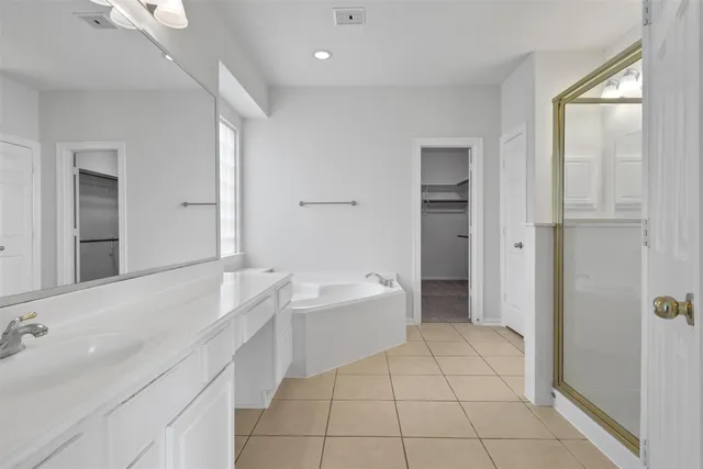 a spacious bathroom with a tub sink and a mirror