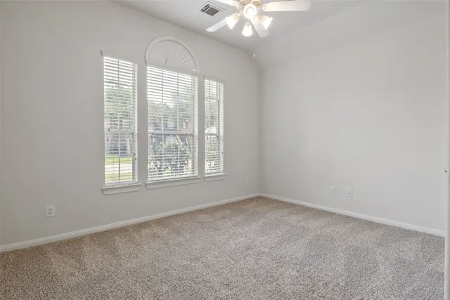 an empty room with a chandelier fan and windows