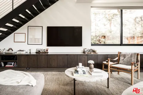 a living room with furniture a flat screen tv and a large window