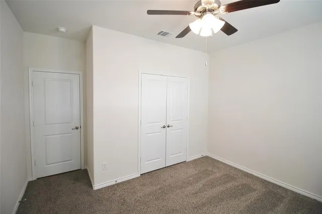an empty room with closet and a chandelier fan