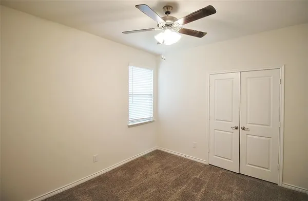 an empty room with a window and a fan