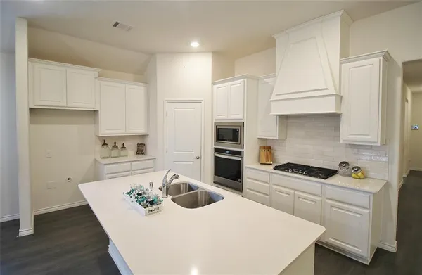 a kitchen with stainless steel appliances kitchen island granite countertop a sink a stove and white cabinets