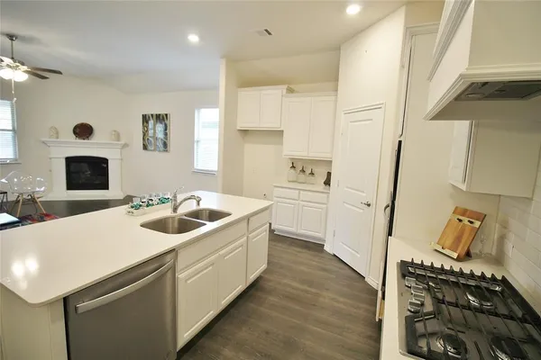 a kitchen with a sink and a stove top oven with wooden floor