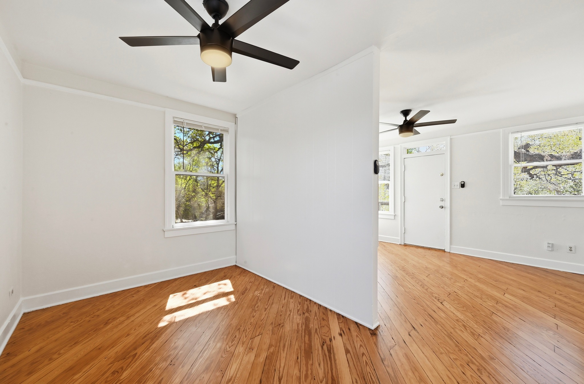 1403 Windsor Road, Unit A Austin, TX 78703 - Photo 8 of 18 an empty room with wooden floor chandelier fan and windows