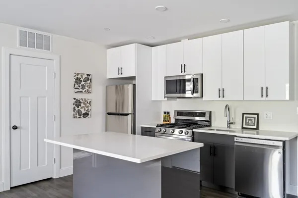 a kitchen with stainless steel appliances a stove a refrigerator a sink and white cabinets