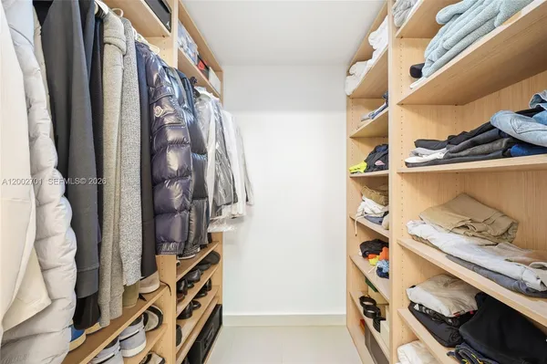 a view of walk in closet with clothes and shoes