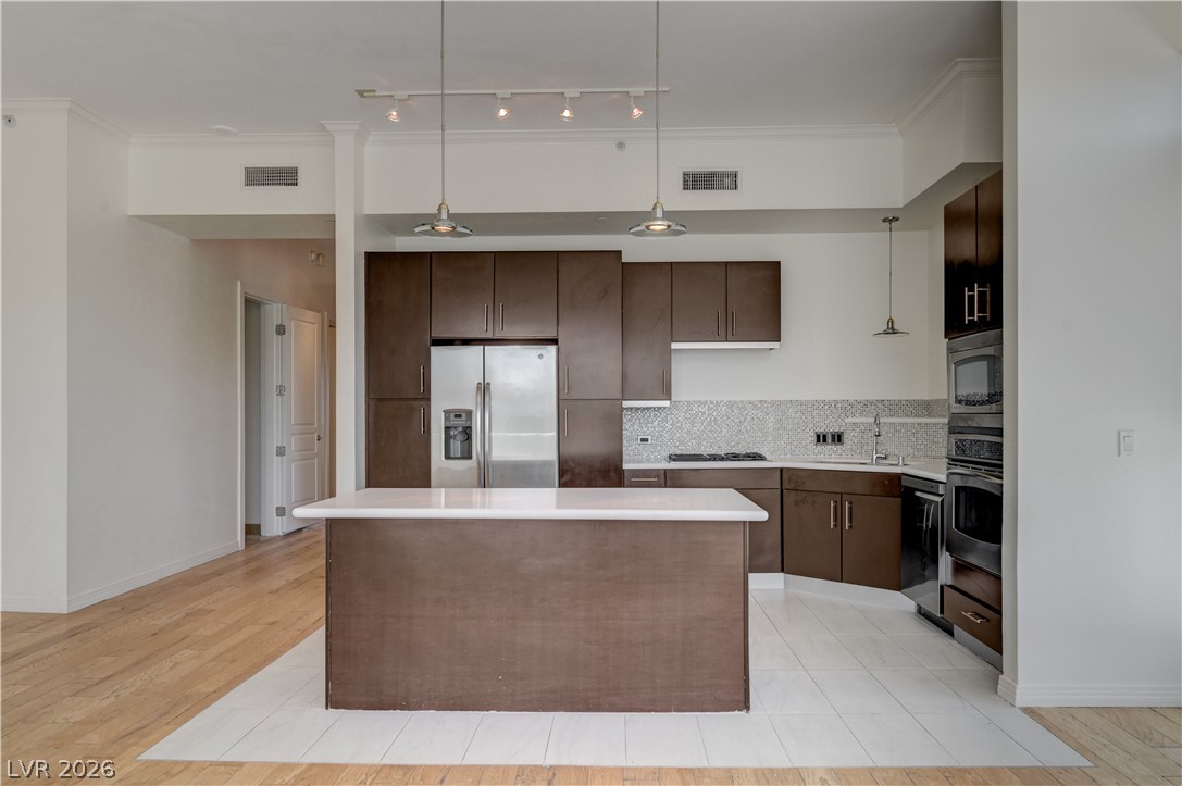 360 East Desert Inn Road, Unit 402 Las Vegas, NV 89109 - Photo 5 of 40 A contemporary kitchen boasts a central island, rich cabinetry, and integrated stainless steel appliances.
