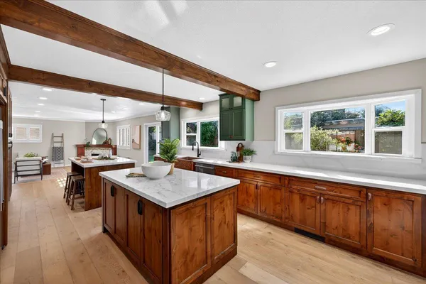 a kitchen with stainless steel appliances granite countertop a refrigerator a sink dishwasher a stove and a dining table with wooden floor