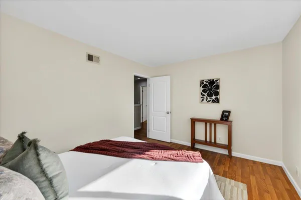 a bedroom with a bed lamp and a large window with wooden floor