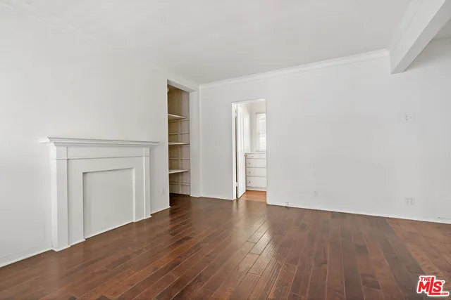 a view of an empty room with wooden floor and closet