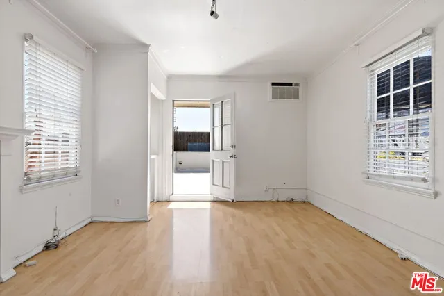 a view of empty room with wooden floor and fan