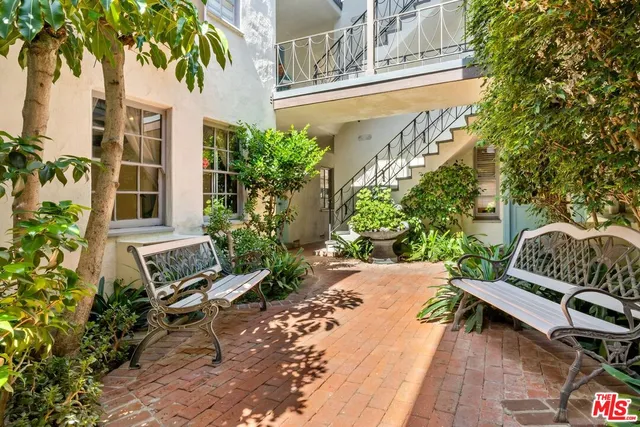 a view of a chair and table in the patio with potted plants and a bench