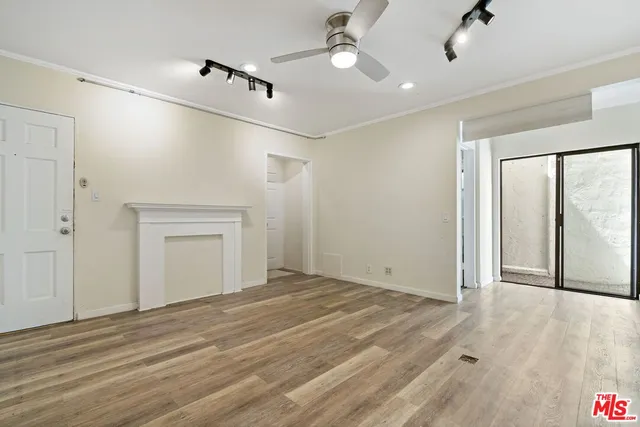 a view of an empty room with glass door and a ceiling fan