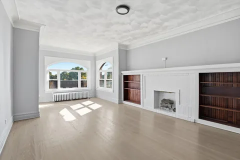 an empty room with windows and fireplace