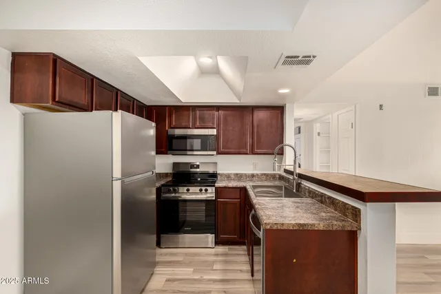 a kitchen with stainless steel appliances granite countertop a refrigerator a stove a sink and a microwave