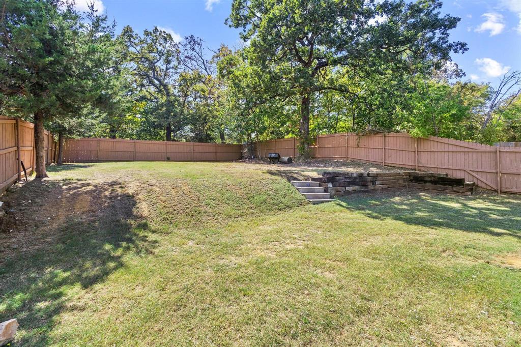 608 East Shepherd Street Denison, TX 75021 - Photo 29 of 31 Expansive backyard featuring a tiered landscape, wooden privacy fencing, and mature trees