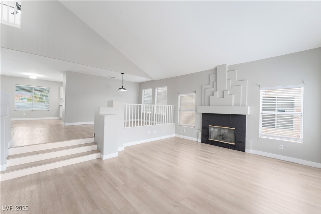 3695 Funston Way Las Vegas, NV 89129 - Photo 11 of 43 Unfurnished living room featuring high vaulted ceiling, light wood-style floors, and a tile fireplace