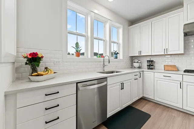 a kitchen with stainless steel appliances a sink dishwasher stove refrigerator and white cabinets with wooden floor