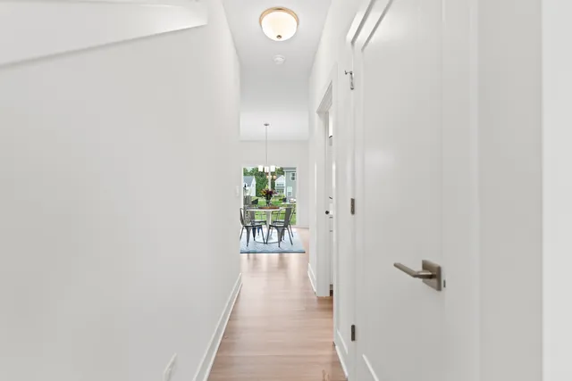 a view of a hallway with wooden floor and a bathroom