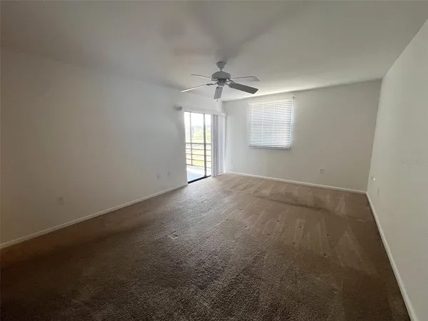 an empty room with a window and a ceiling fan