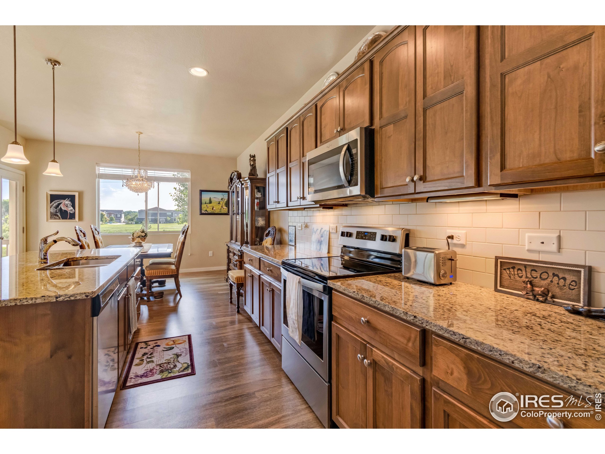 7213 Horsechestnut Street Wellington, CO 80549 - Photo 16 of 39 a kitchen with stainless steel appliances granite countertop a stove a sink dishwasher and cabinets with wooden floor