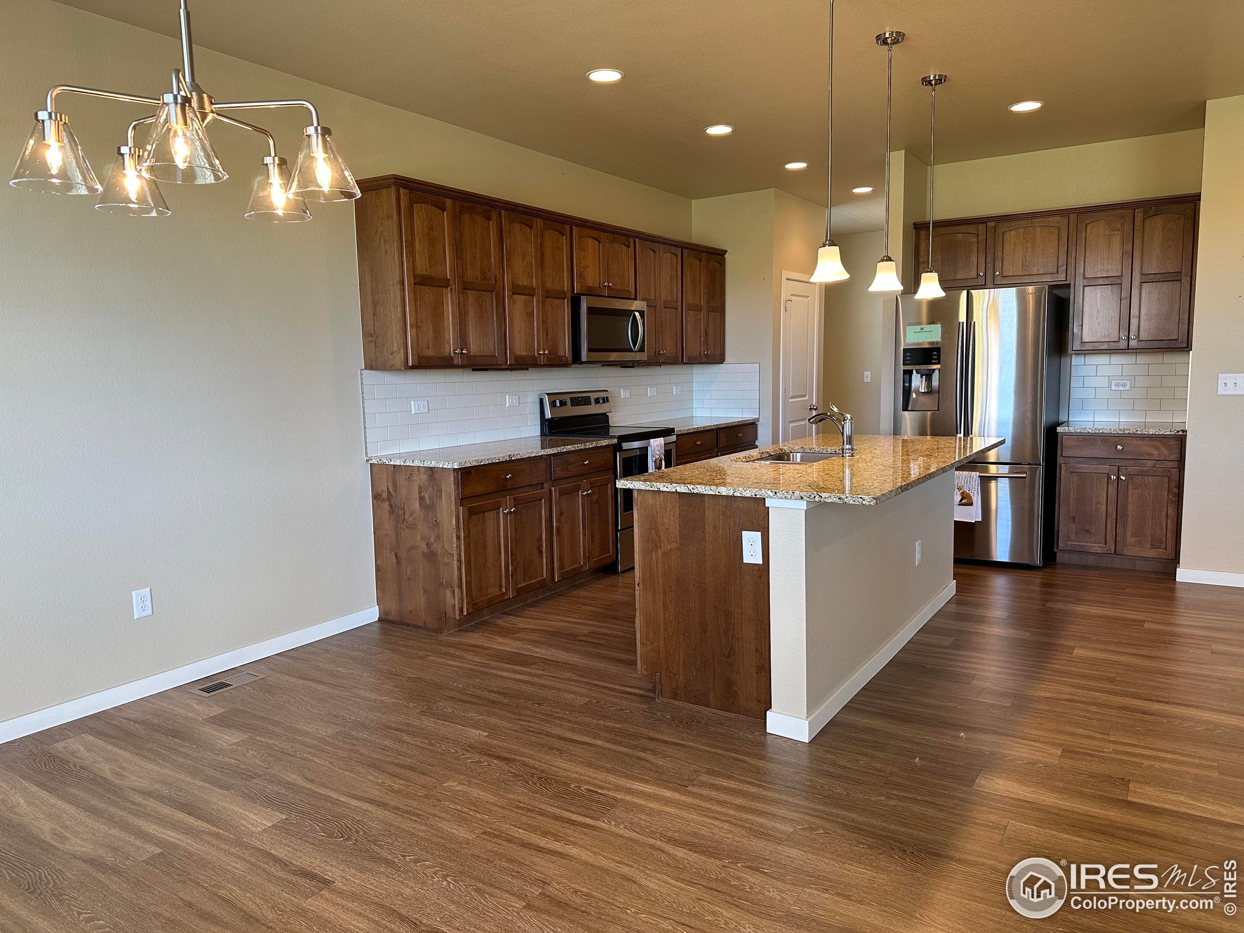 7213 Horsechestnut Street Wellington, CO 80549 - Photo 18 of 39 a kitchen with stainless steel appliances granite countertop a sink a stove and a refrigerator