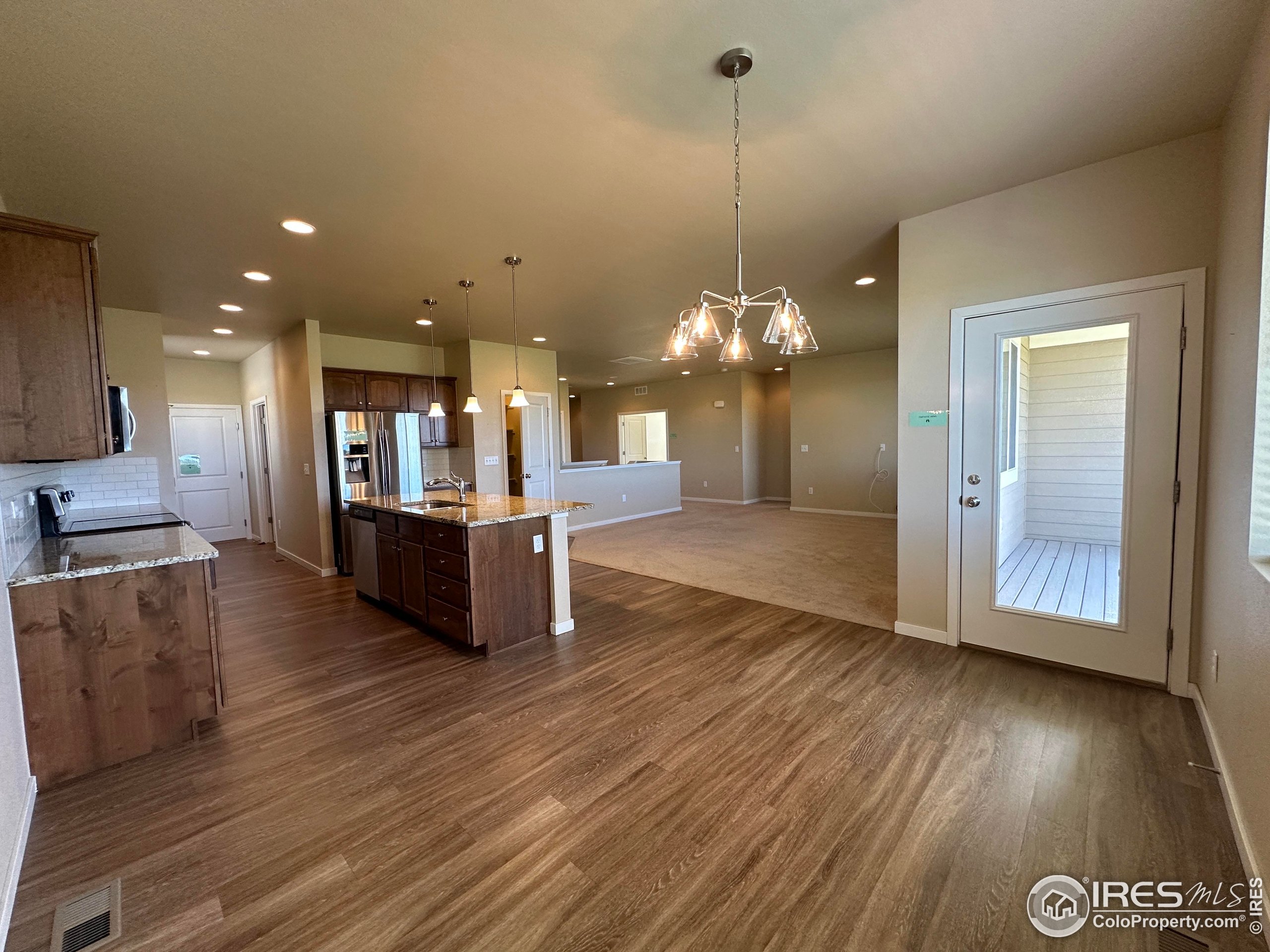 7213 Horsechestnut Street Wellington, CO 80549 - Photo 26 of 39 a view of a kitchen with kitchen island granite countertop wooden floors and a sink