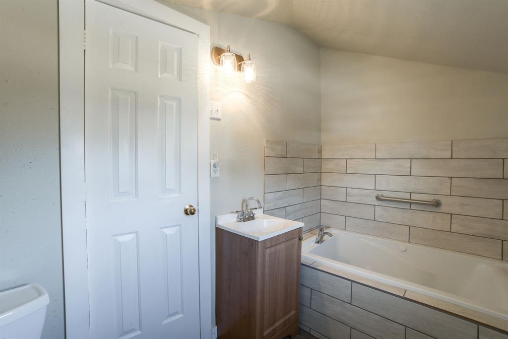300 South Wall Street Itasca, TX 76055 - Photo 23 of 34 a bathroom with a tub a sink and a window