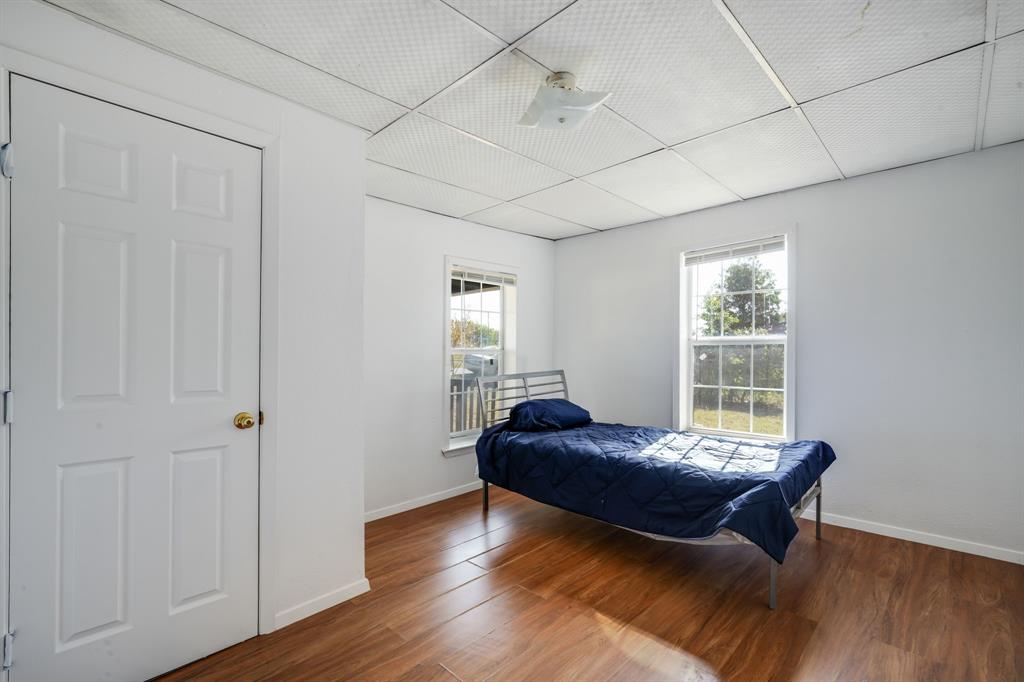 300 South Wall Street Itasca, TX 76055 - Photo 25 of 34 a bedroom with a bed and wooden floor