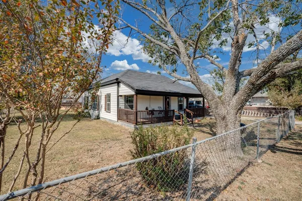 a view of house with a yard and large tree