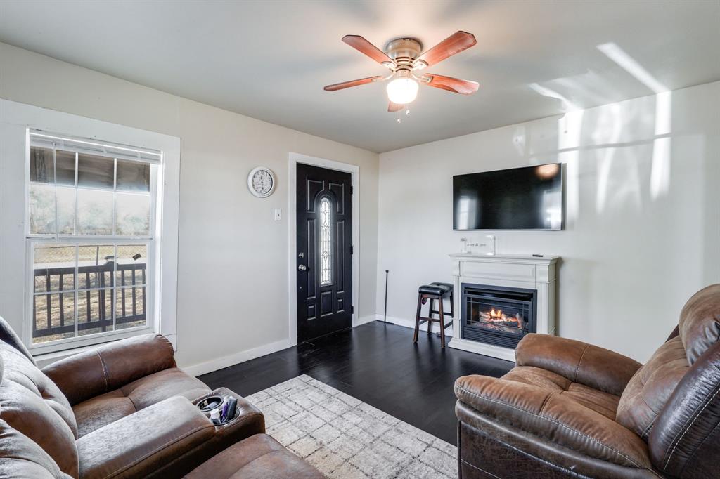 300 South Wall Street Itasca, TX 76055 - Photo 7 of 34 a living room with furniture a fireplace and a flat screen tv
