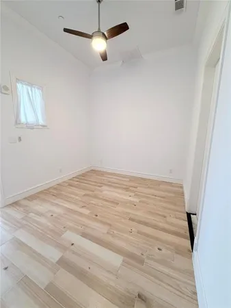 an empty room with wooden floor fan and window