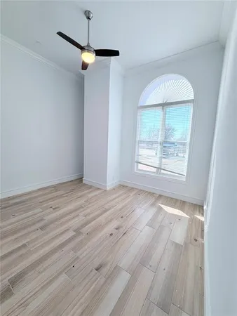 an empty room with wooden floor cabinet and windows