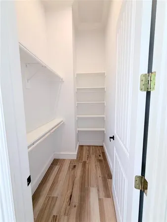 a walk in closet with wooden floor