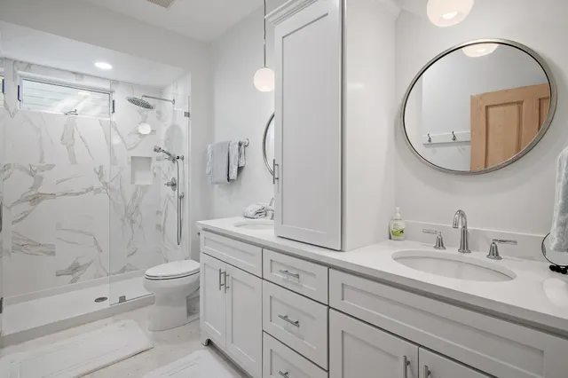 a bathroom with a double vanity sink toilet mirror and bathtub
