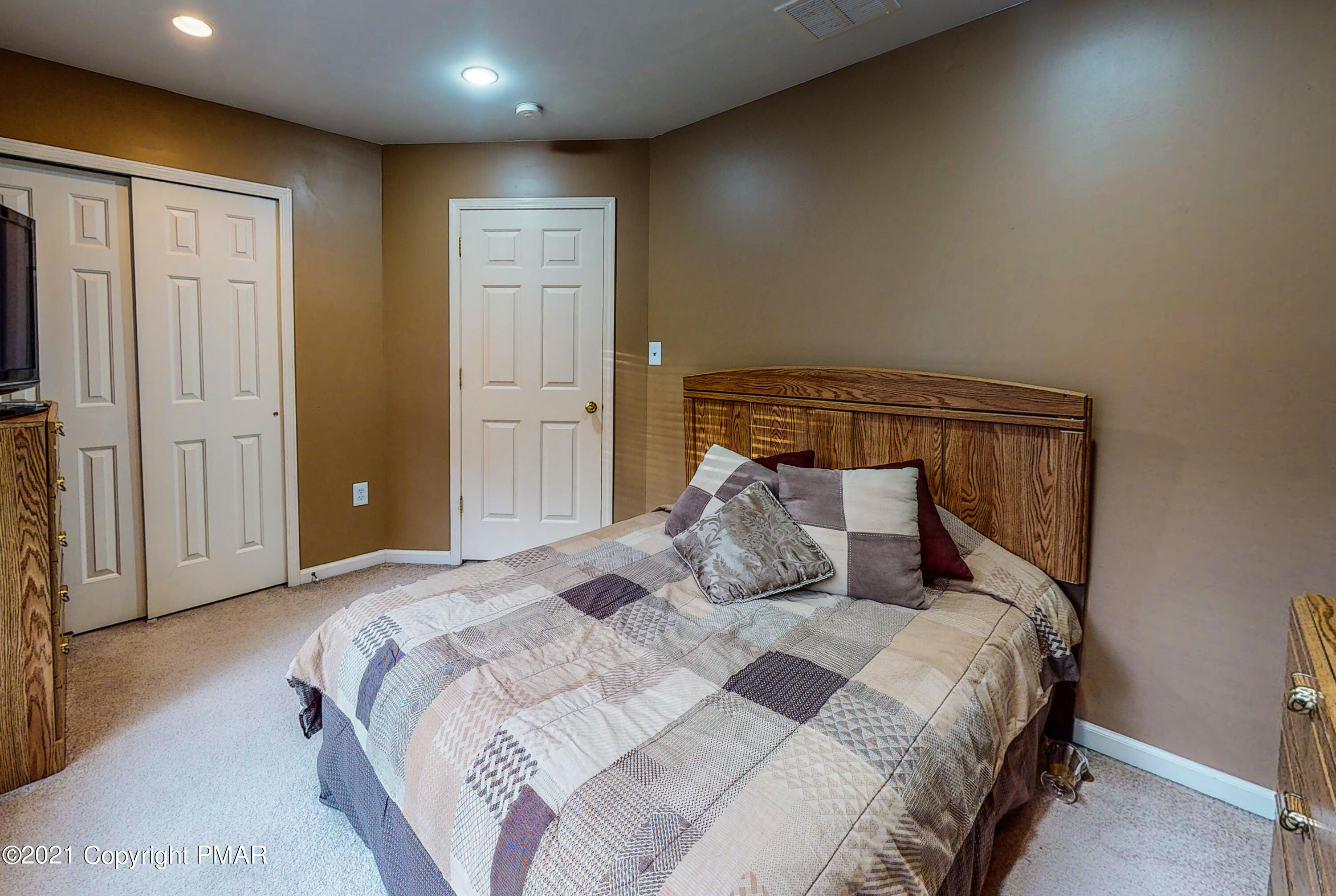 5631 Decker Road Bushkill, PA 18324 - Photo 30 of 61 a bedroom with a large bed and a chandelier