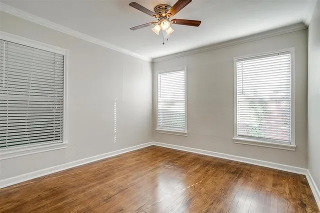 a view of an empty room with window and a chandelier fan