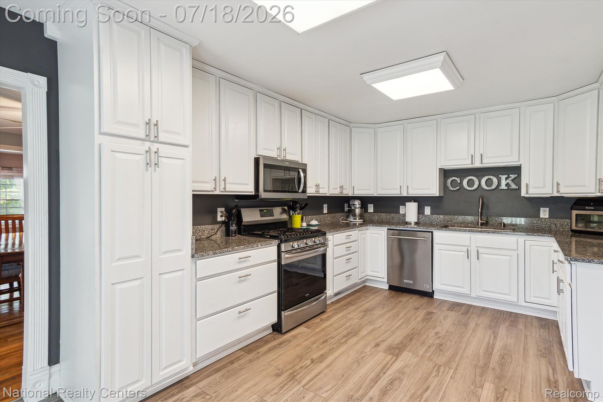 9589 Clinton Macon Road Tecumseh, MI 49286 - Photo 20 of 48 Kitchen featuring white cabinetry, stainless steel appliances, granite countertops, wood-finish flooring, and recessed ceiling lighting