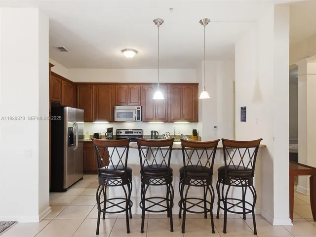 a kitchen with stainless steel appliances a dining table chairs and white cabinets