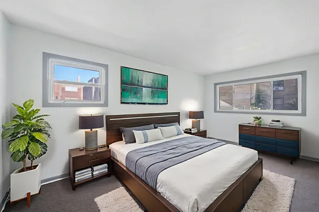 a bedroom with a bed and a potted plant on the dresser