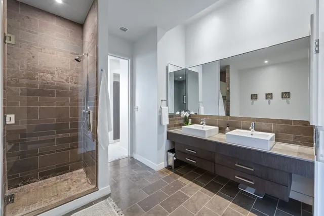 a bathroom with a double vanity sink mirror and shower