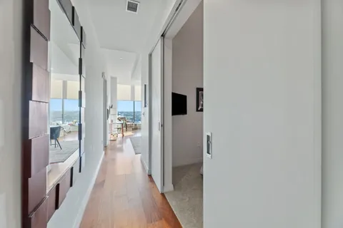 a view of a hallway with wooden floor and a living room