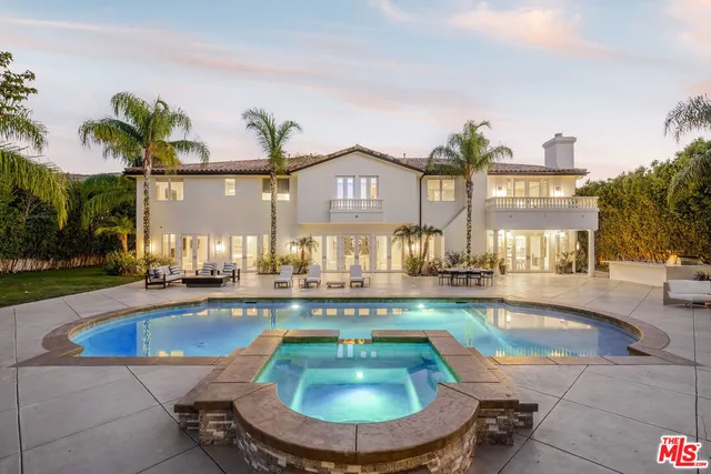 a view of a brick house with potted plants and large trees